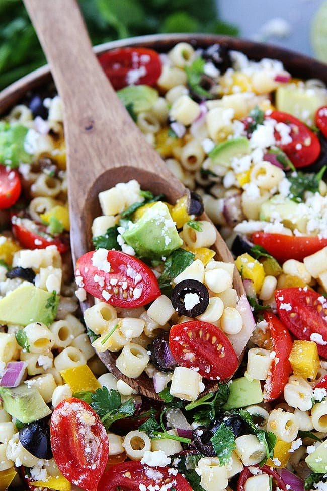 Southwest Pasta Salad is the BEST pasta salad recipe and perfect for potlucks, parties, and easy meals! #pasta #pastasalad #summer #tomatoes #dressing #sidedish #easyrecipe #dinner #vegetarian #salad Southwest Pasta Salad on wooden spoon.