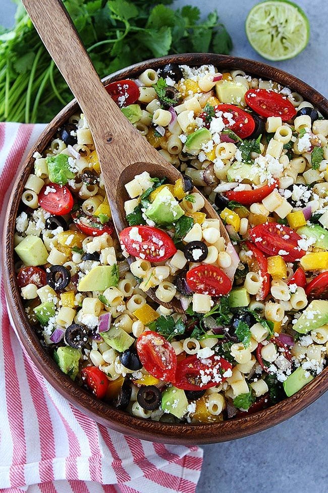 Southwest Pasta Salad is the BEST pasta salad recipe and perfect for potlucks, parties, and easy meals! #pasta #pastasalad #summer #tomatoes #dressing #sidedish #easyrecipe #dinner #vegetarian #salad Southwest pasta salad in bowl with wooden spoon.