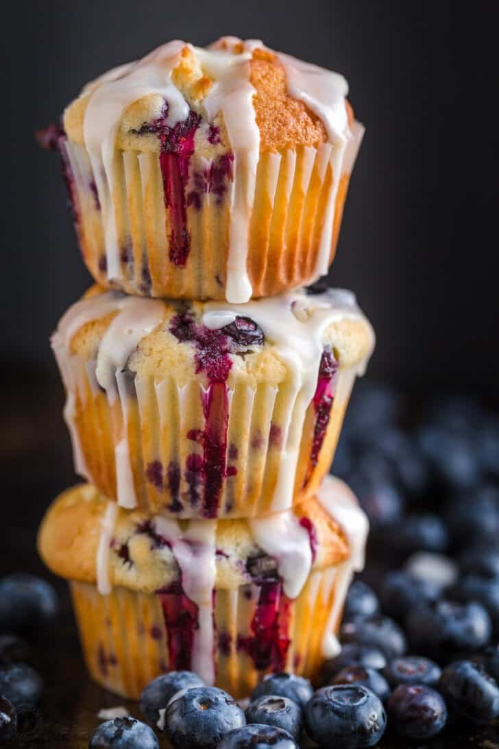 Blueberry Muffins glazed and stacked surrounded by fresh blueberries