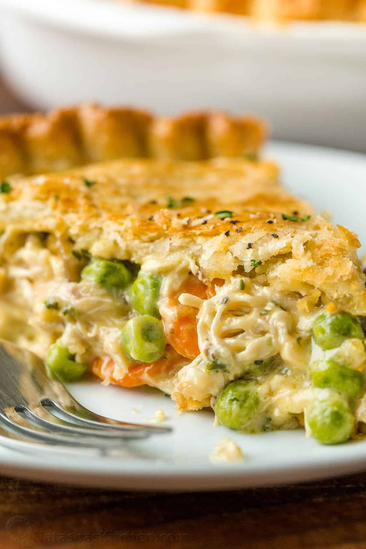 Chicken pot pie, filled with chicken and vegetables, sliced and served on a plate with fork