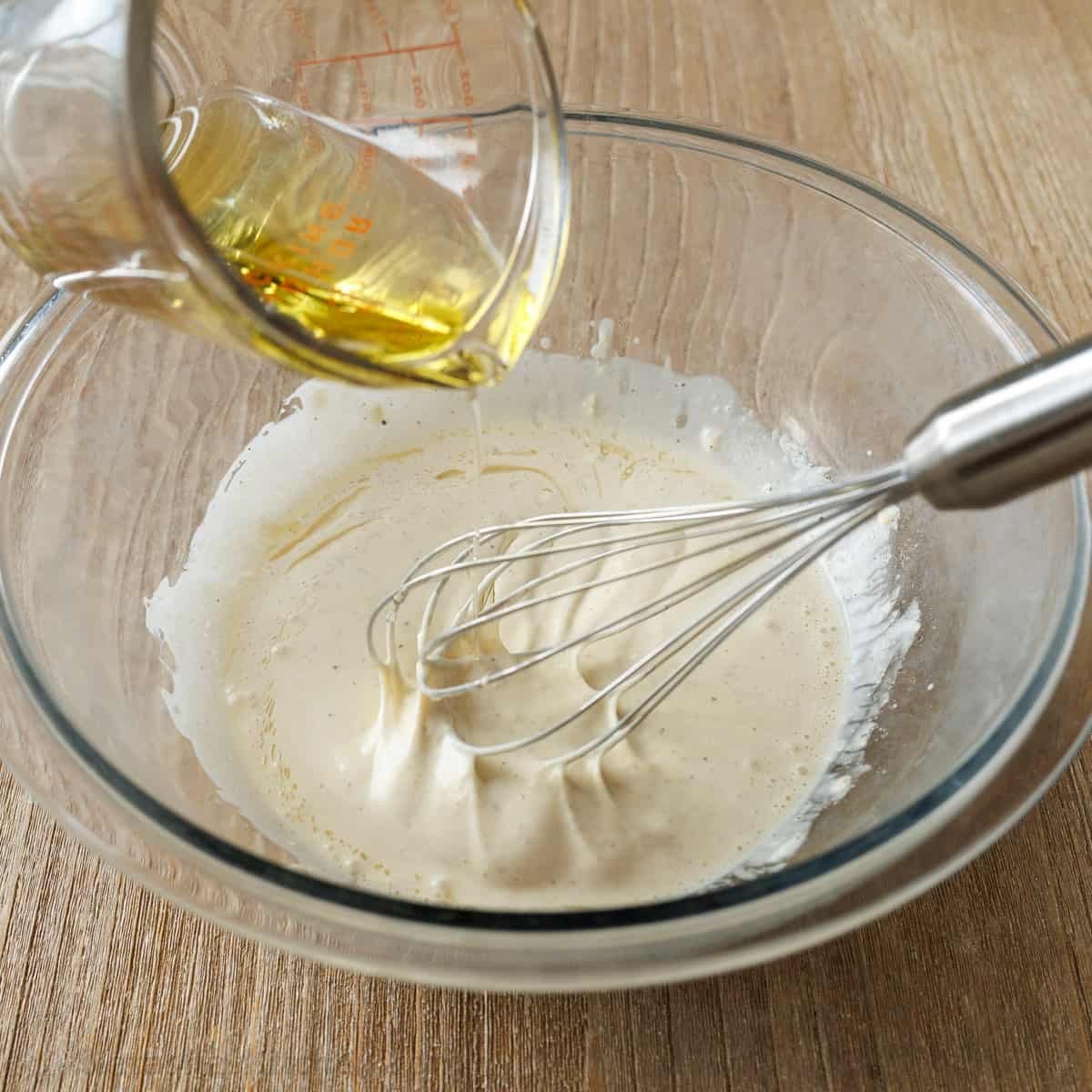 Slowly drizzling in olive oil while whisking
