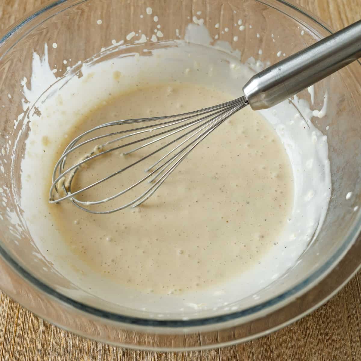 Whisking caesar dressing to combine cheese