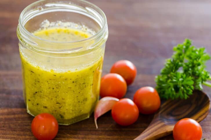 Italian Dressing in mason jar with tomatoes and parsley on the side