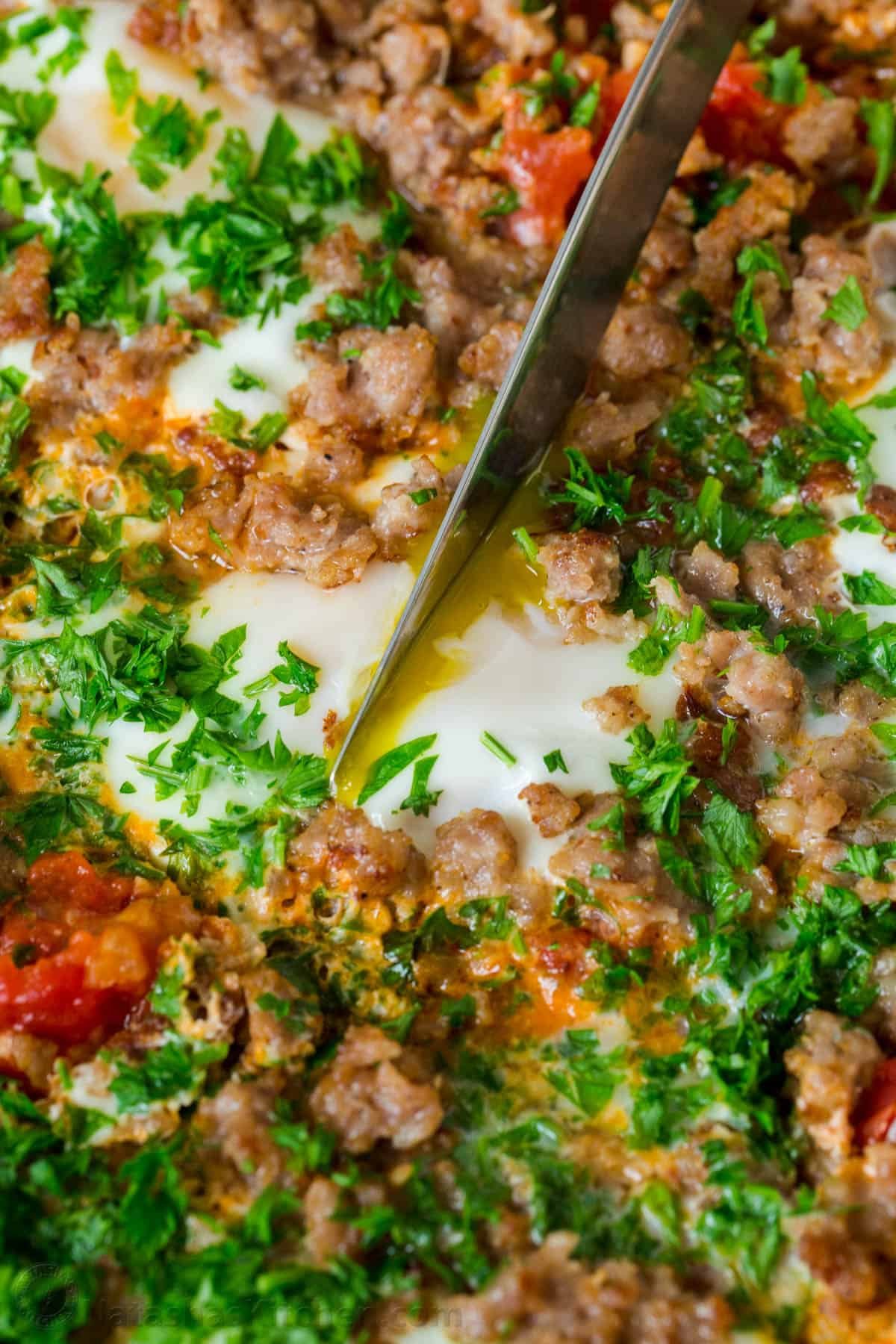 Cutting through a soft egg in breakfast Shakshuka skillet