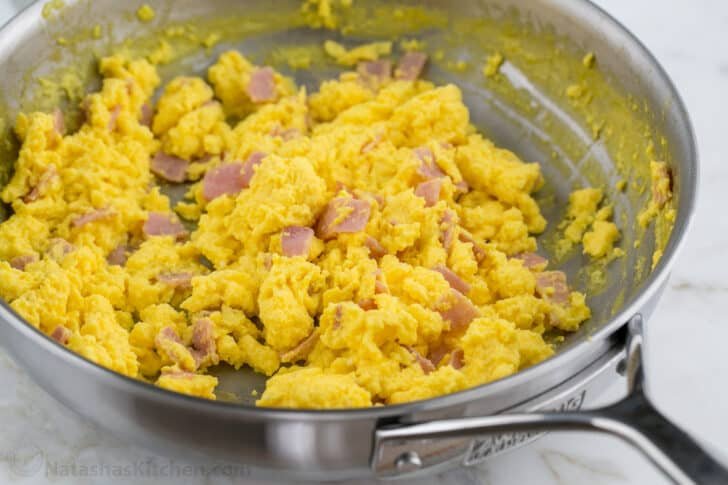 These Breakfast Burritos will make a breakfast person out of you. Crisp on the outside and filled with egg, ham, and cheese. Easy freezer breakfast burritos! Scrambled eggs and ham in a pan