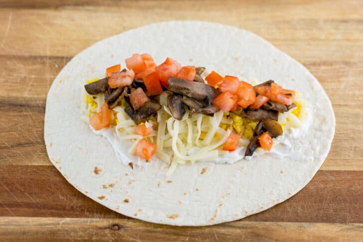These Breakfast Burritos will make a breakfast person out of you. Crisp on the outside and filled with egg, ham, and cheese. Easy freezer breakfast burritos! Add diced tomato and sautéed mushrooms to your breakfast burrito