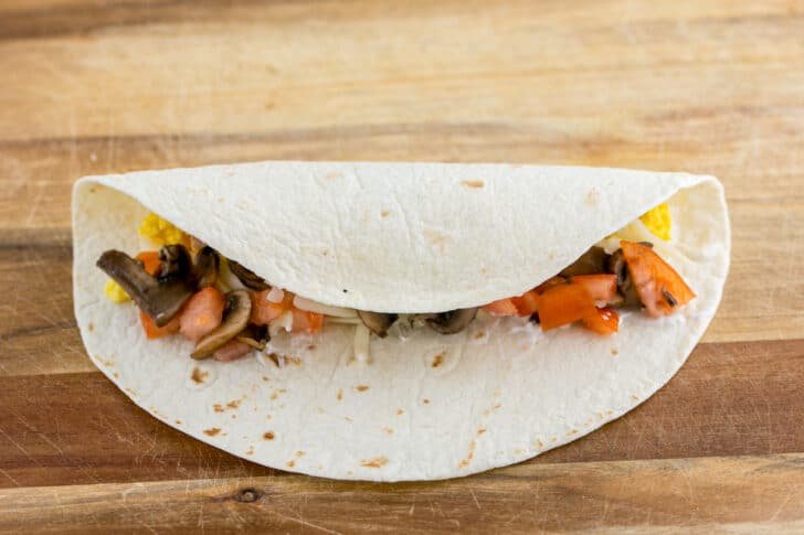 These Breakfast Burritos will make a breakfast person out of you. Crisp on the outside and filled with egg, ham, and cheese. Easy freezer breakfast burritos! Fold one end of tortilla over the filling to begin wrapping your breakfast burrito