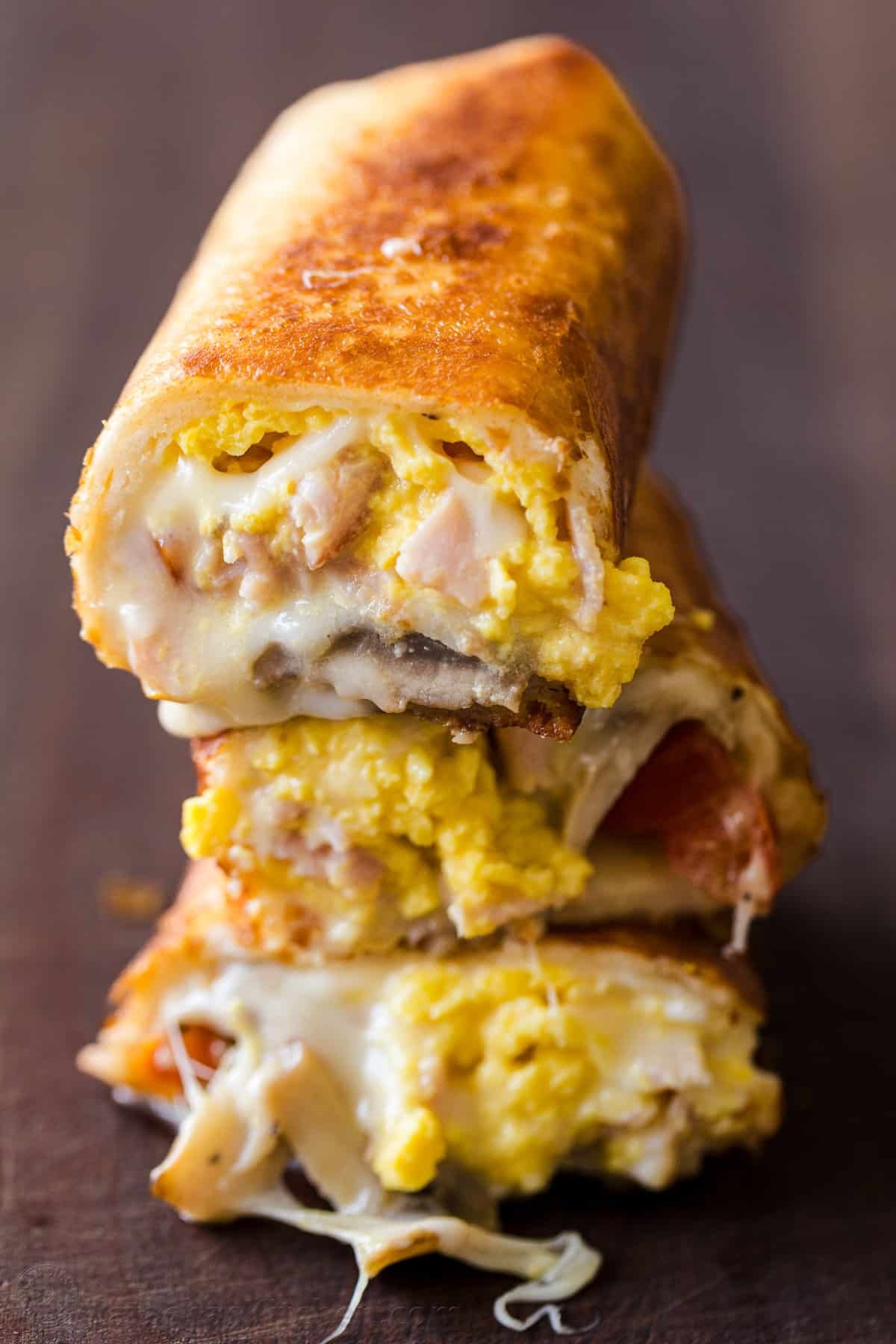 These Breakfast Burritos will make a breakfast person out of you. Crisp on the outside and filled with egg, ham, and cheese. Easy freezer breakfast burritos! Breakfast burrito with melted cheese, scrambled eggs, and ham wrapped in a crisp golden brown tortilla