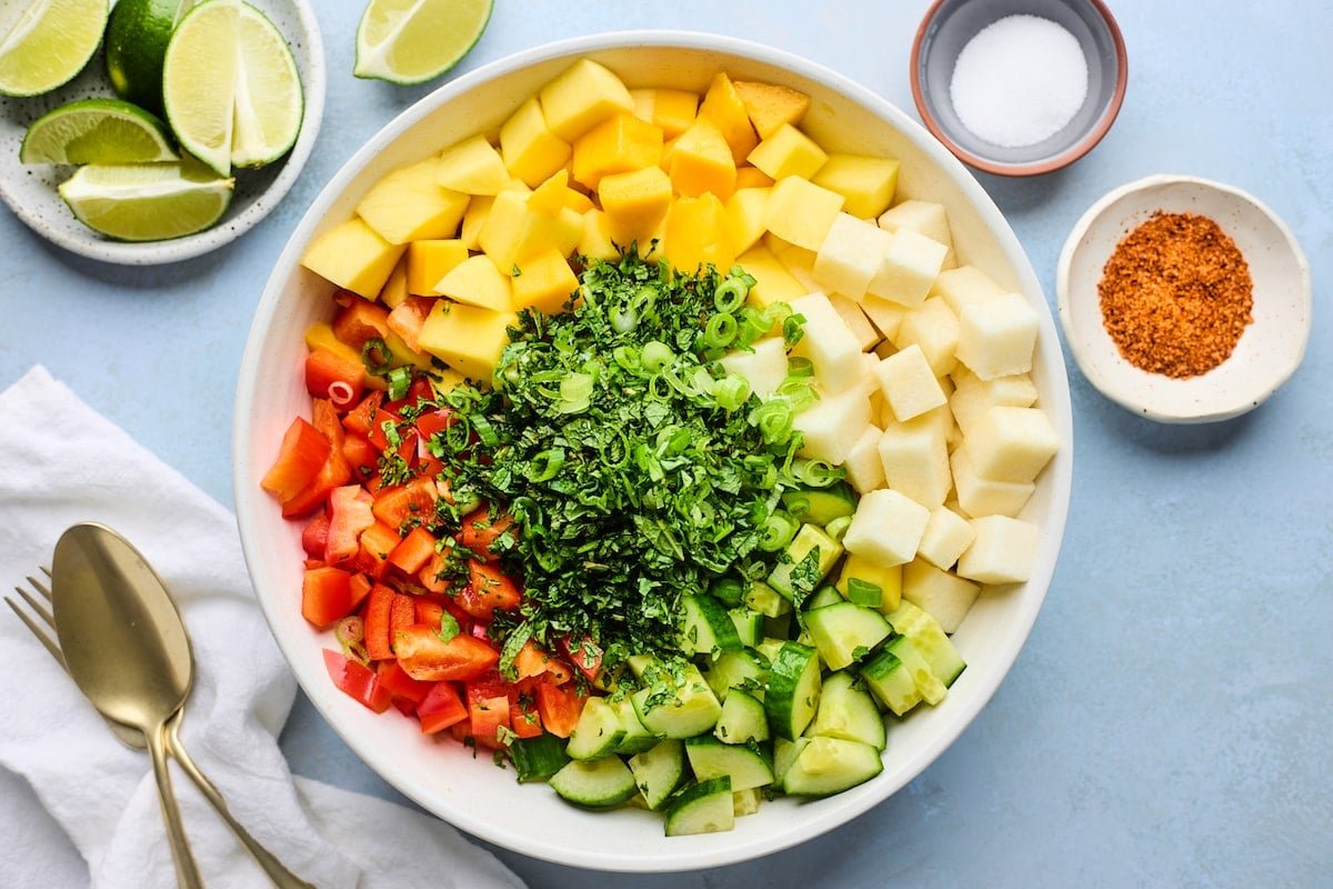 mango, jicama, cucumber, red pepper, cilantro, green onion chopped in bowl.
