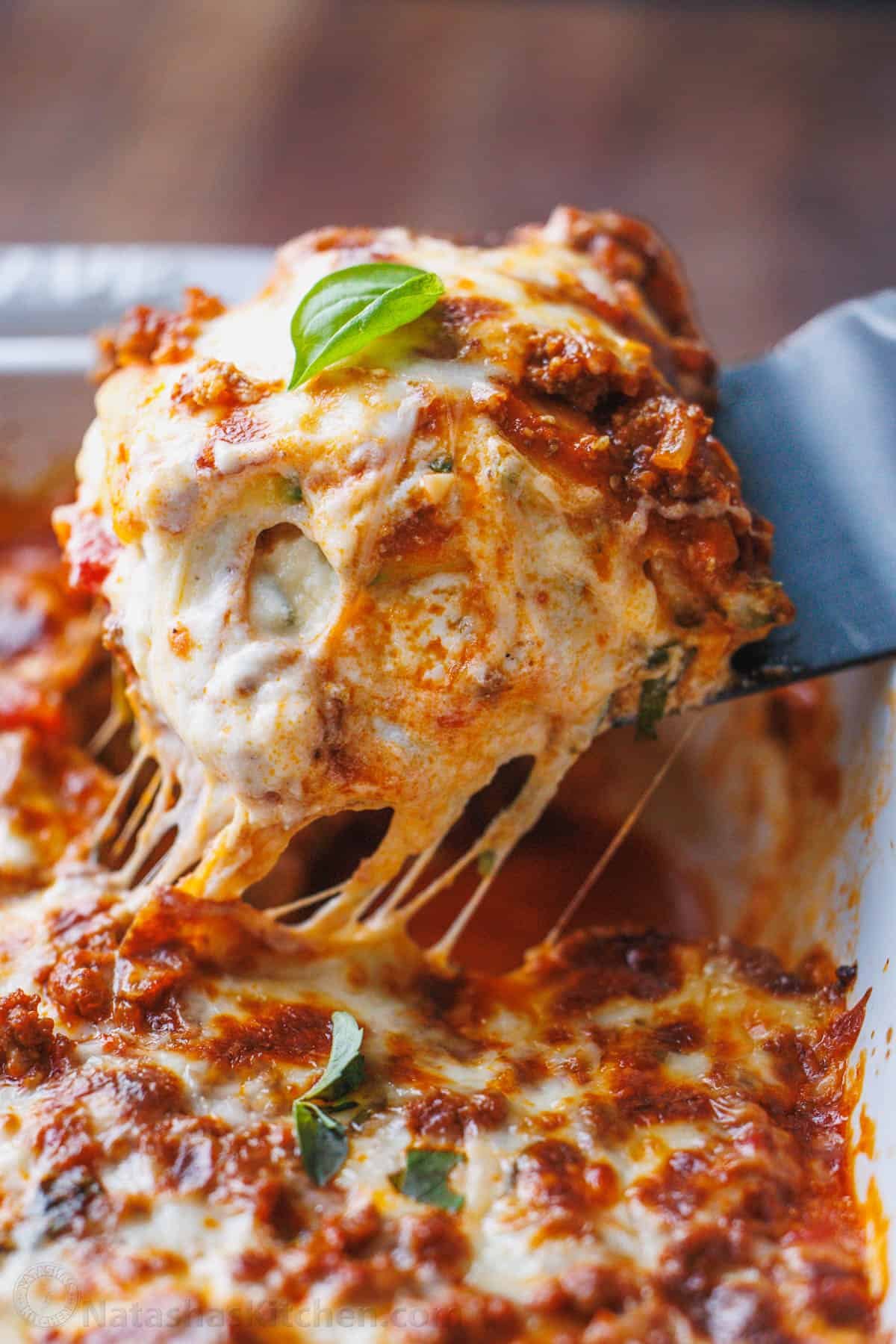 Zucchini lasagna tastes just like the cheesy traditional Italian recipe but with fewer calories and more nutrients. You won't miss the pasta! close up photo of zucchini lasagna being served
