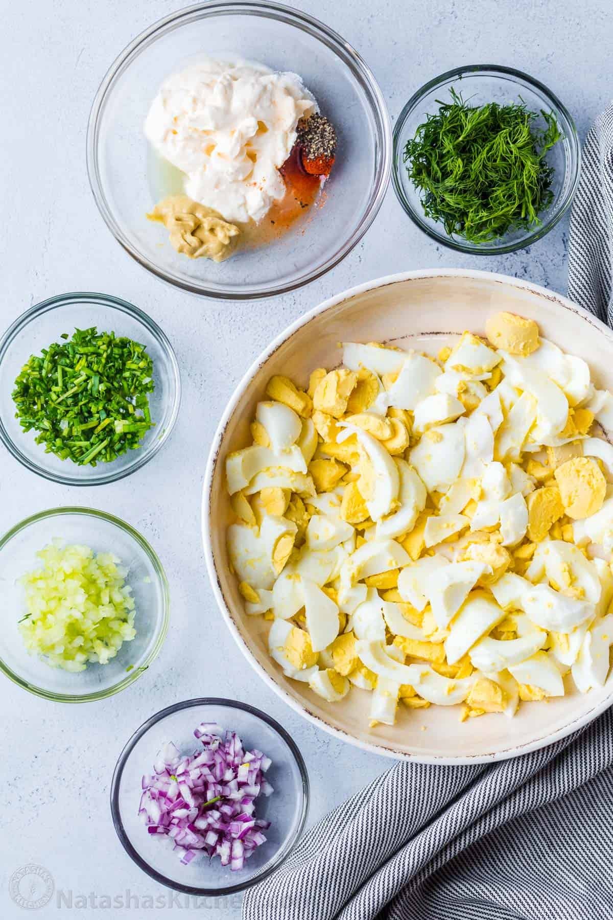 Truly the Best Egg Salad Recipe. Hard-boiled eggs with celery, dill, seasoning and chives in creamy dressing. Egg salad is a great way to use cooked eggs! Chopped ingredients in individual bowls before mixing.