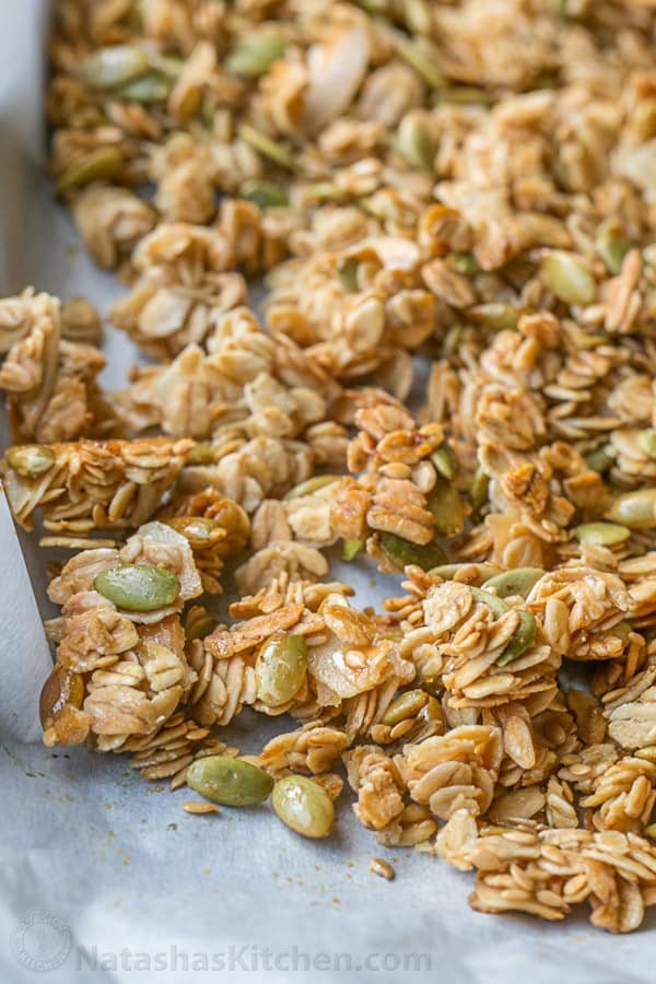 umpkin Flax Granola Recipe - crunchy, clustery and sweetened with honey | natashaskitchen.com baked homemade granola on a baking sheet to show crunchy cluster texture