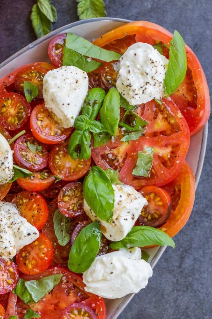 Tomato Burrata Salad is one of the easiest Summer salads. The rich burrata cheese is delicious with tomatoes, basil, olive oil, and balsamic. tomato burrata salad on a plate