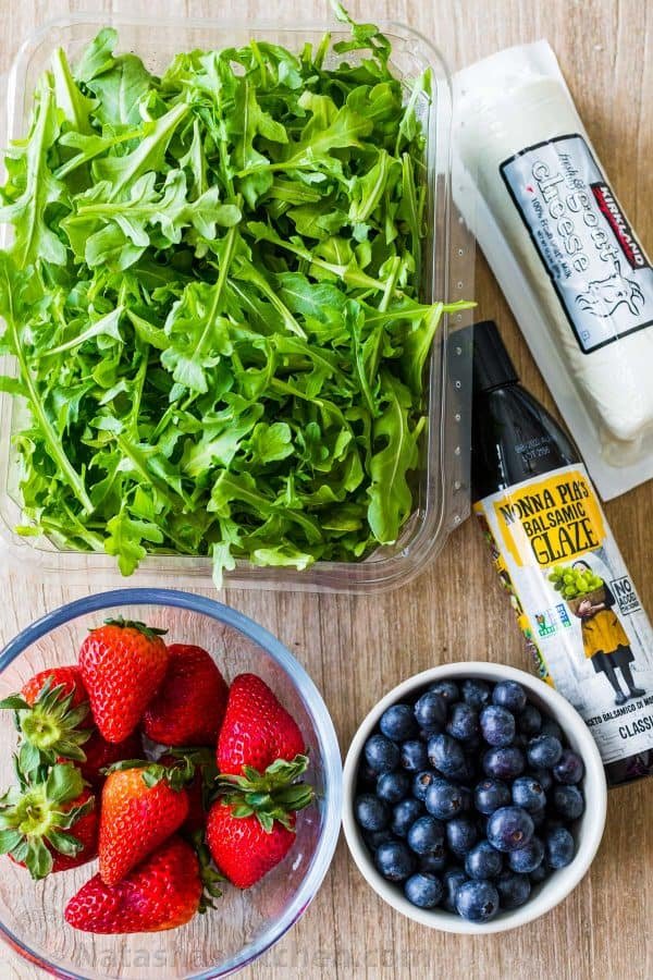 Arugula salad ingredients with fresh arugula, goat cheese, strawberries, blueberries and balsamic glaze