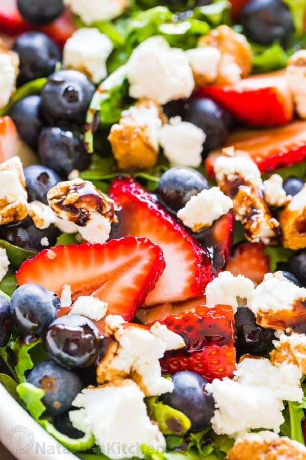 Up close arugula salad recipe with berries and goat cheese