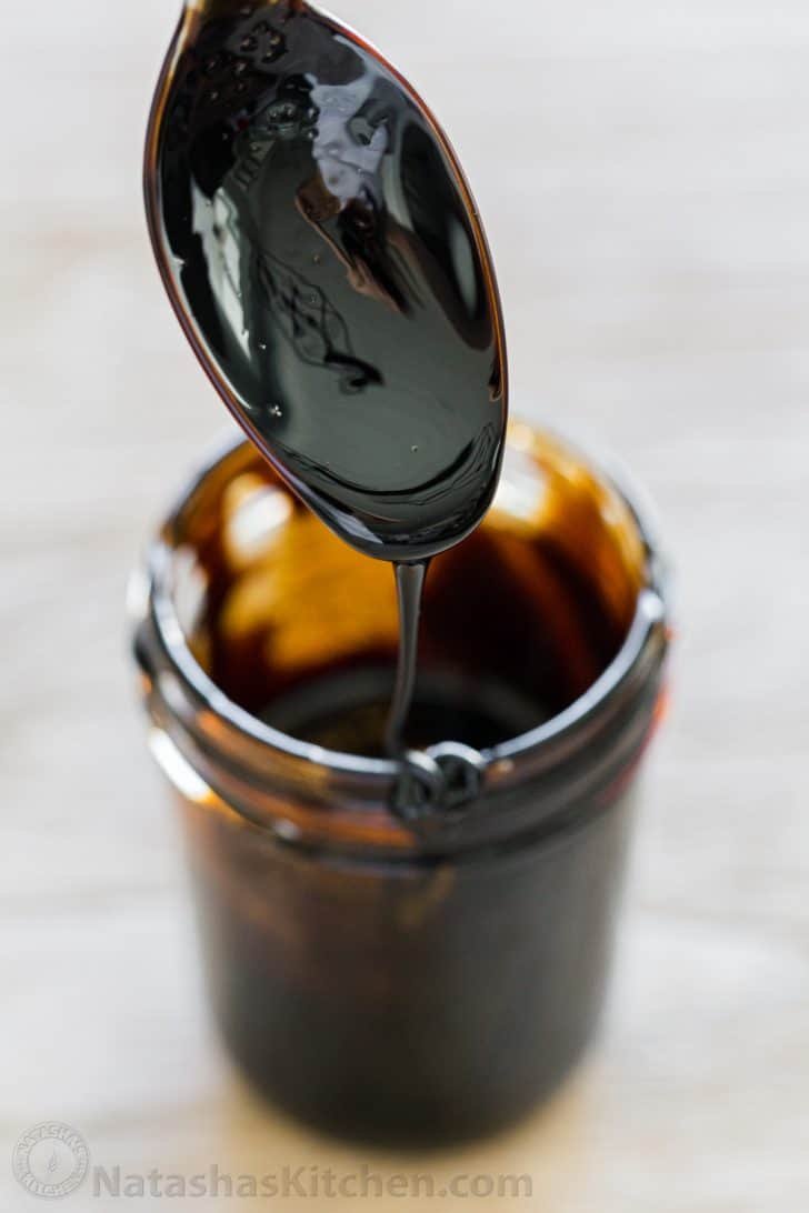 Balsamic Glaze dripping off a spoon into a glass jar