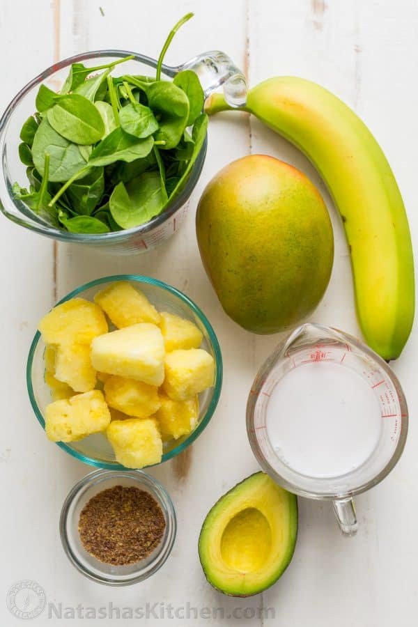 Ingredients for smoothie bowl recipe including mango, avocado, banana, pineapple, spinach, flax seeds and coconut milk 