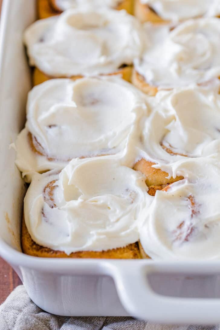 Big, soft, homemade Cinnamon Rolls have the best cream cheese icing and they always disappear fast. As my sister puts it, they are "better than Cinnabon!" #cinnamonrolls #cinnamonrollrecipe #cinnamonrollsrecipe #sweetbuns #cinnamonrollsicing #natashaskitchen #thanksgiving #christmas yeast dough cinnamon rolls glazed with icing in pan
