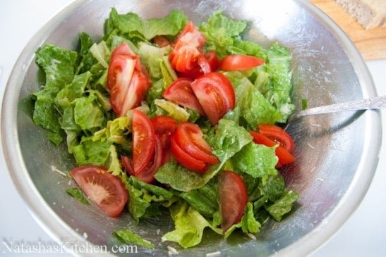 Tomatoes added into bowl with romaine lettuce 