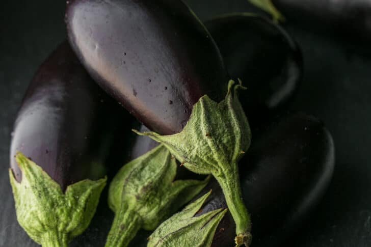 This Baked Eggplant Parmesan recipe fills your mouth with crisp eggplant, flavorful marinara, and plenty of melted cheese to replicate a classic Italian dish. Garden fresh eggplant ready for slicing to make baked Eggplant Parmesan