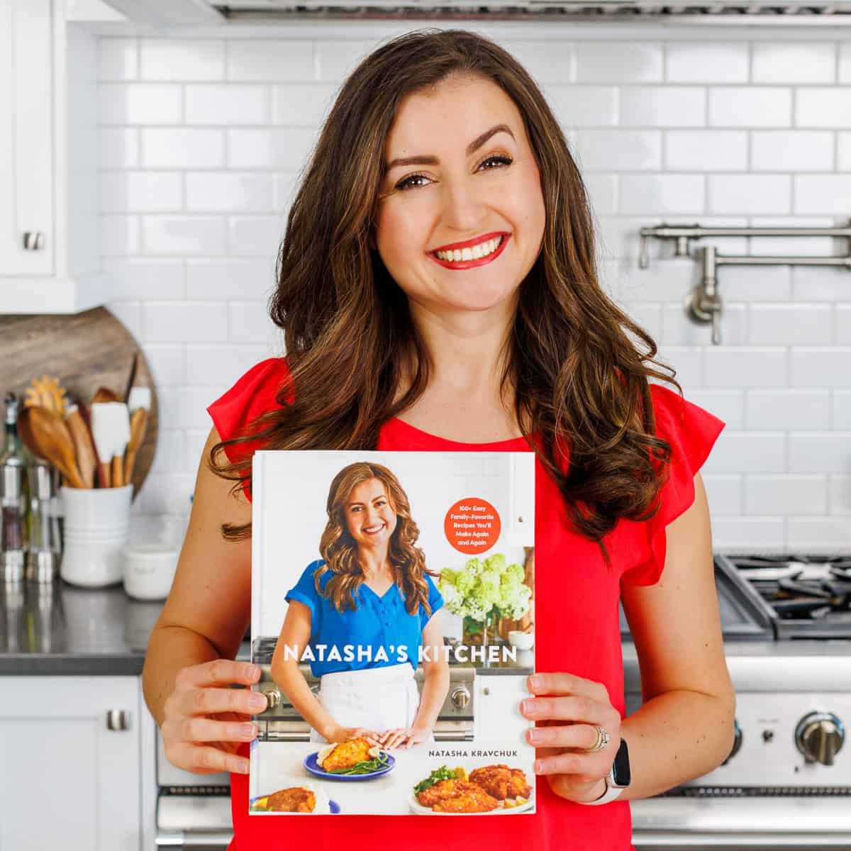 Natasha's Kitchen debut cookbook Natasha holding Natasha's Kitchen debut cookbook