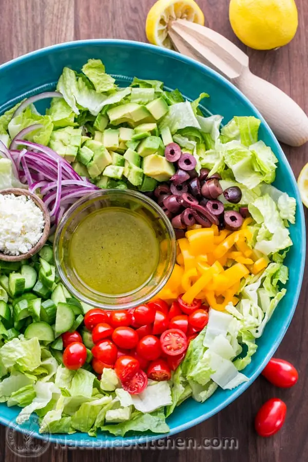 How to make the Best Greek Salad Recipe! Fresh Greek Salad is a must try! So healthy with cucumber, tomato, avocado, olives and feta. You will want the easy Greek dressing on all of your salads! How to make Greek salad prepared in a mixing bowl with dressing in separate container