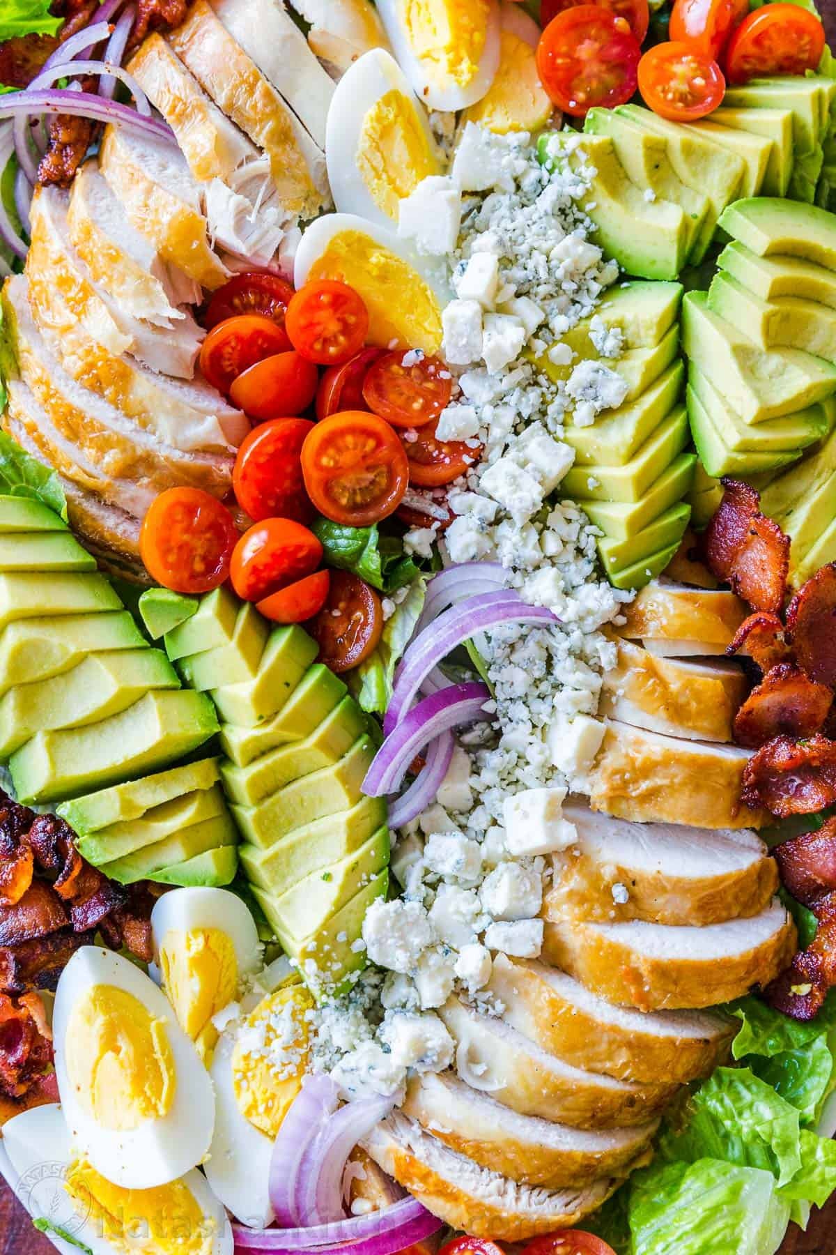 Easy Chicken Cobb Salad with the Best Cobb Salad Dressing! A protein-packed salad loaded with lettuce, tomatoes, chicken, avocado and cheese. Up close arrangement of chicken Cobb salad with avocado, bacon, cheese, egg, tomato and onion