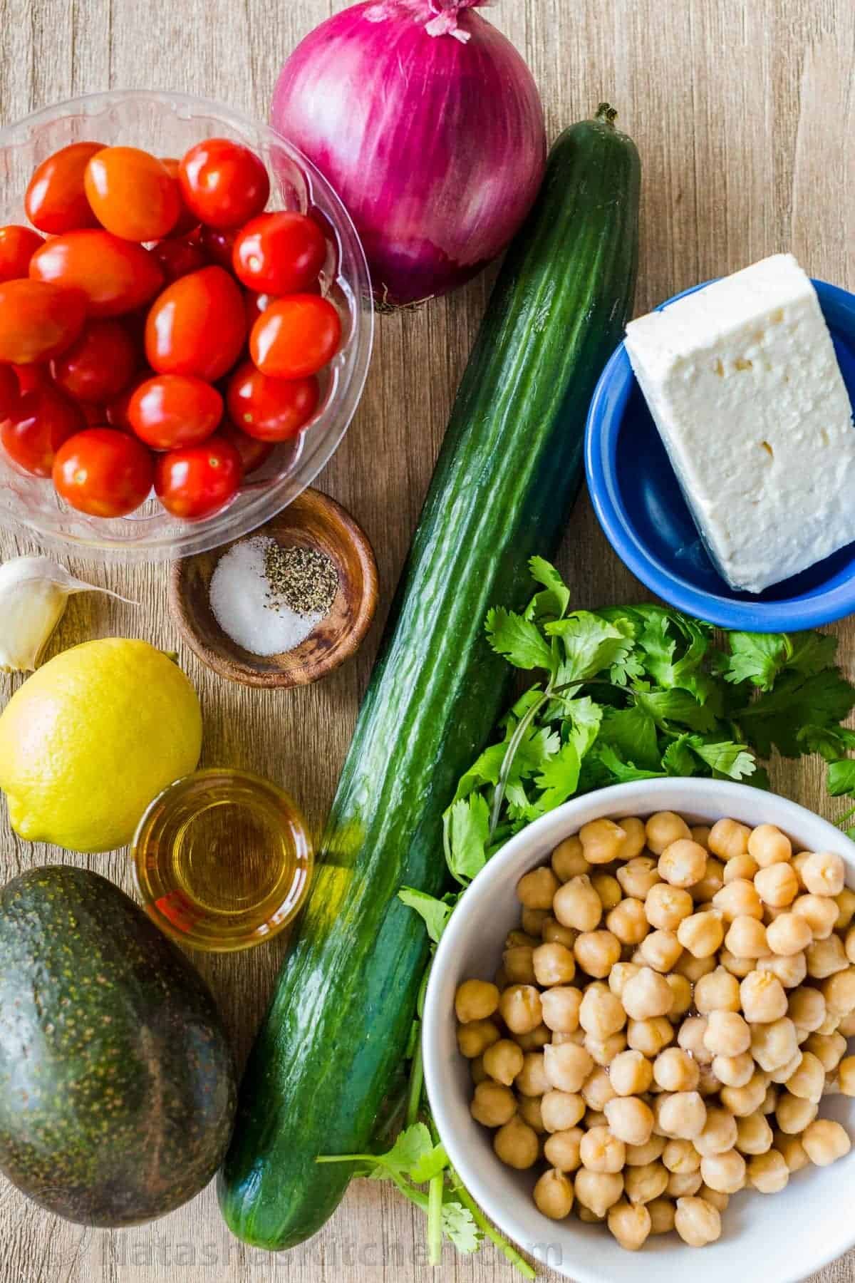 Chickpea Salad loaded with crisp cucumbers, juicy tomatoes, creamy avocado, feta cheese and chickpeas or garbanzo beans. Fresh, healthy and protein packed! #chickpeasalad #garbanzobeansalad #chickpeas #chickpeasaladrecipe #salad #saladrecipe #fetacheese #tomatosalad #avocadosalad #greeksalad #mediterraneansalad #natashaskitchen chickpea salad ingredients with healthy chickpeas, cucumber, tomato, avocado, cilantro and feta cheese