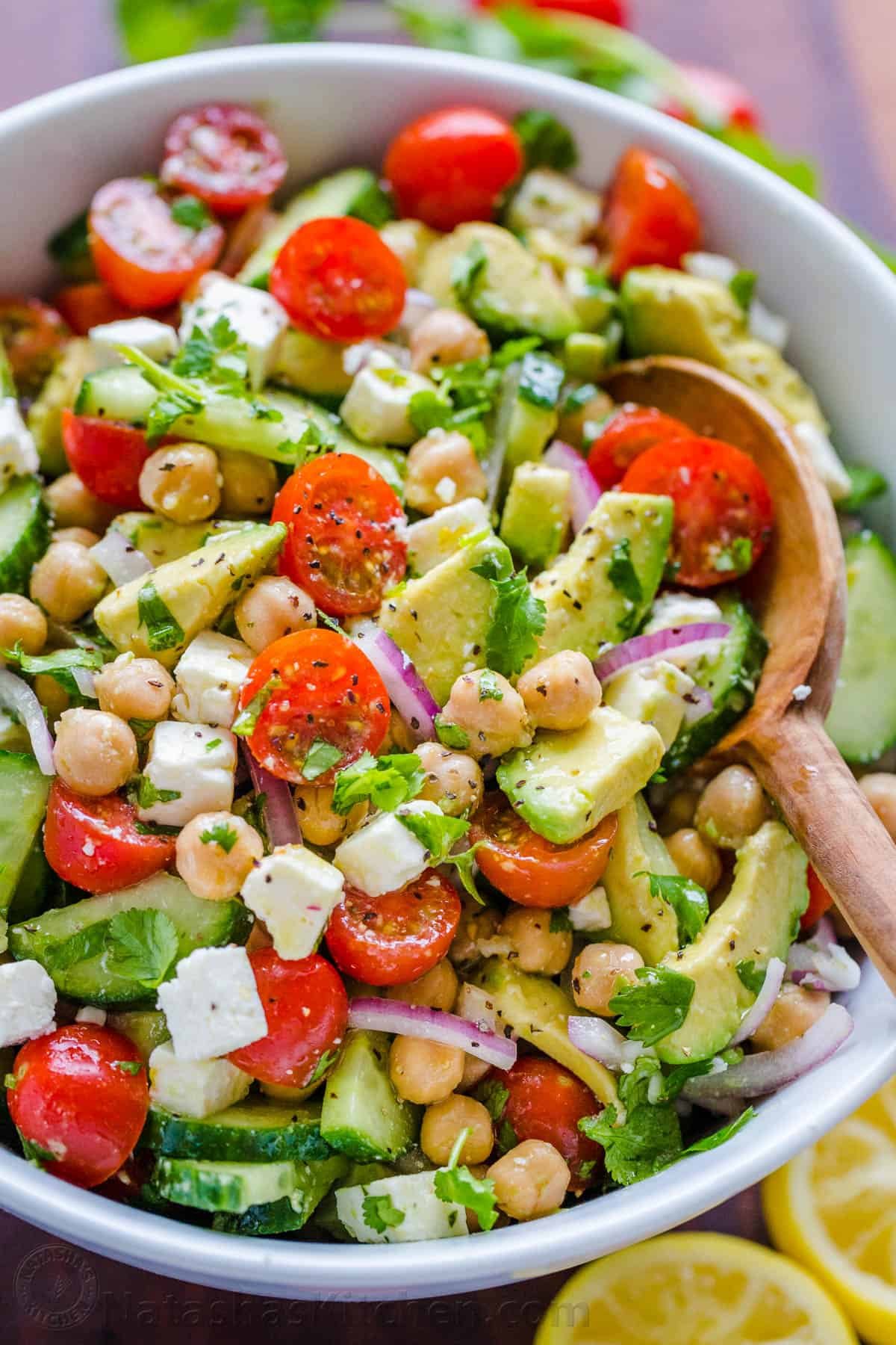 Chickpea Salad loaded with crisp cucumbers, juicy tomatoes, creamy avocado, feta cheese and chickpeas or garbanzo beans. Fresh, healthy and protein packed! #chickpeasalad #garbanzobeansalad #chickpeas #chickpeasaladrecipe #salad #saladrecipe #fetacheese #tomatosalad #avocadosalad #greeksalad #mediterraneansalad #natashaskitchen Chickpea Salad tossed together with lemon dressing in salad bowl