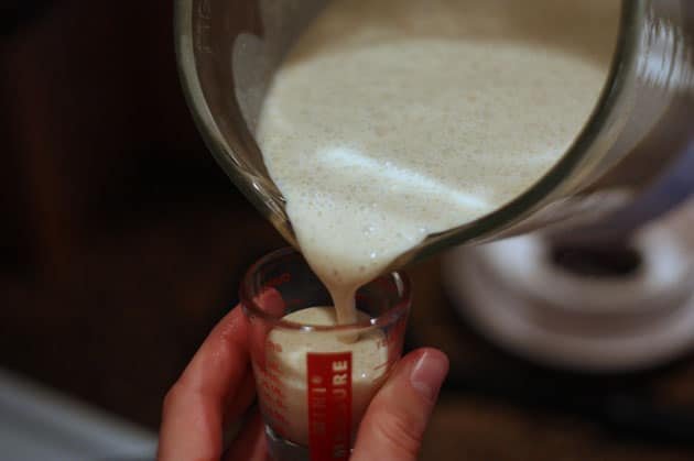 A mixture is poured into a one-ounce measuring cup 