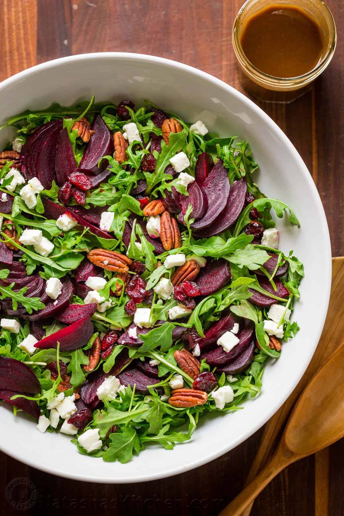 This beet salad recipe tastes fancy but is SO EASY to make. A show-stopping and flavorful salad that is impressive for holidays, entertaining, or dinner at home. Arugula salad topped with beets, feta cheese, and pecans in a large bowl with balsamic dressing on the side