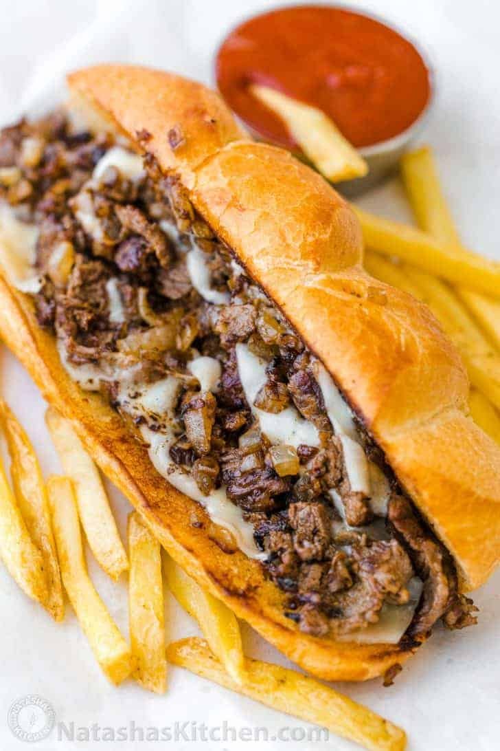 Philly cheesesteak served on hoagie roll with fries and ketchup