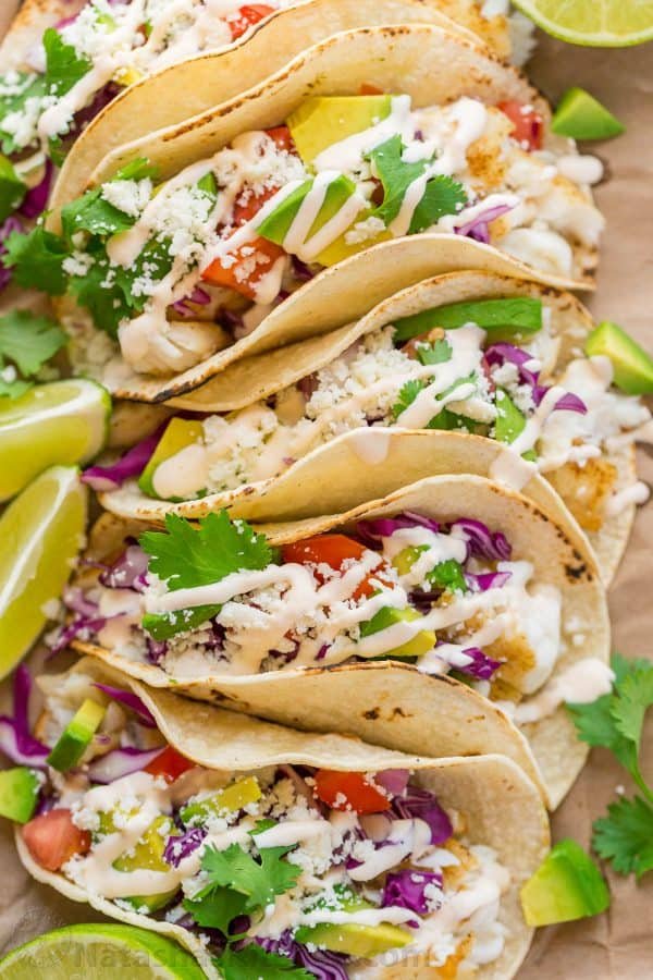 A close up of Fish Tacos with fish sauce on top of the tacos. 