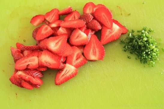 Green onion and strawberries cut on a cutting board 