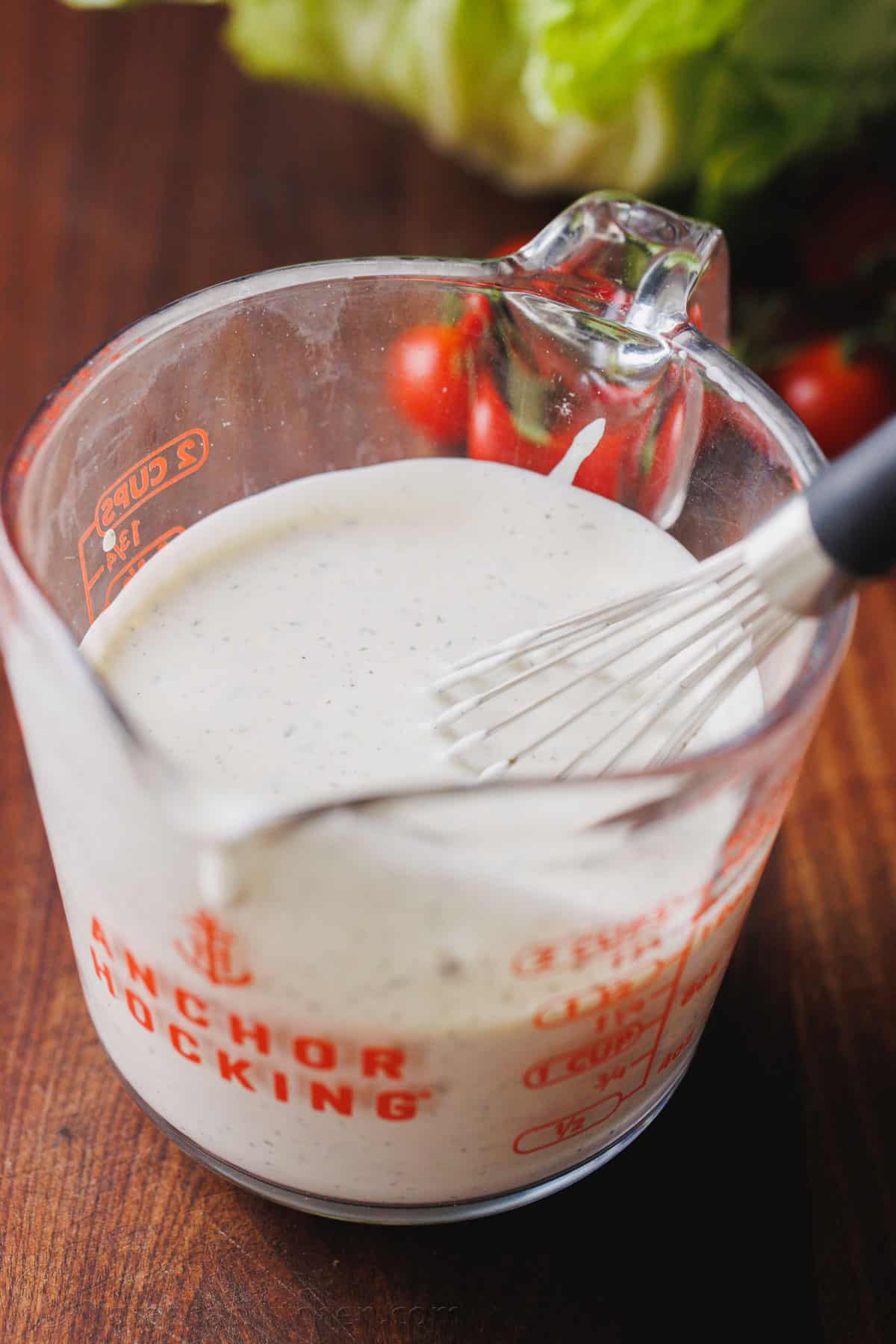 Make restaurant-style buttermilk Ranch Dressing in seconds! This creamy homemade ranch recipe is perfect as a salad dressing or as a dip. Buttermilk ranch dressing in a glass measuring cup with a whisk.