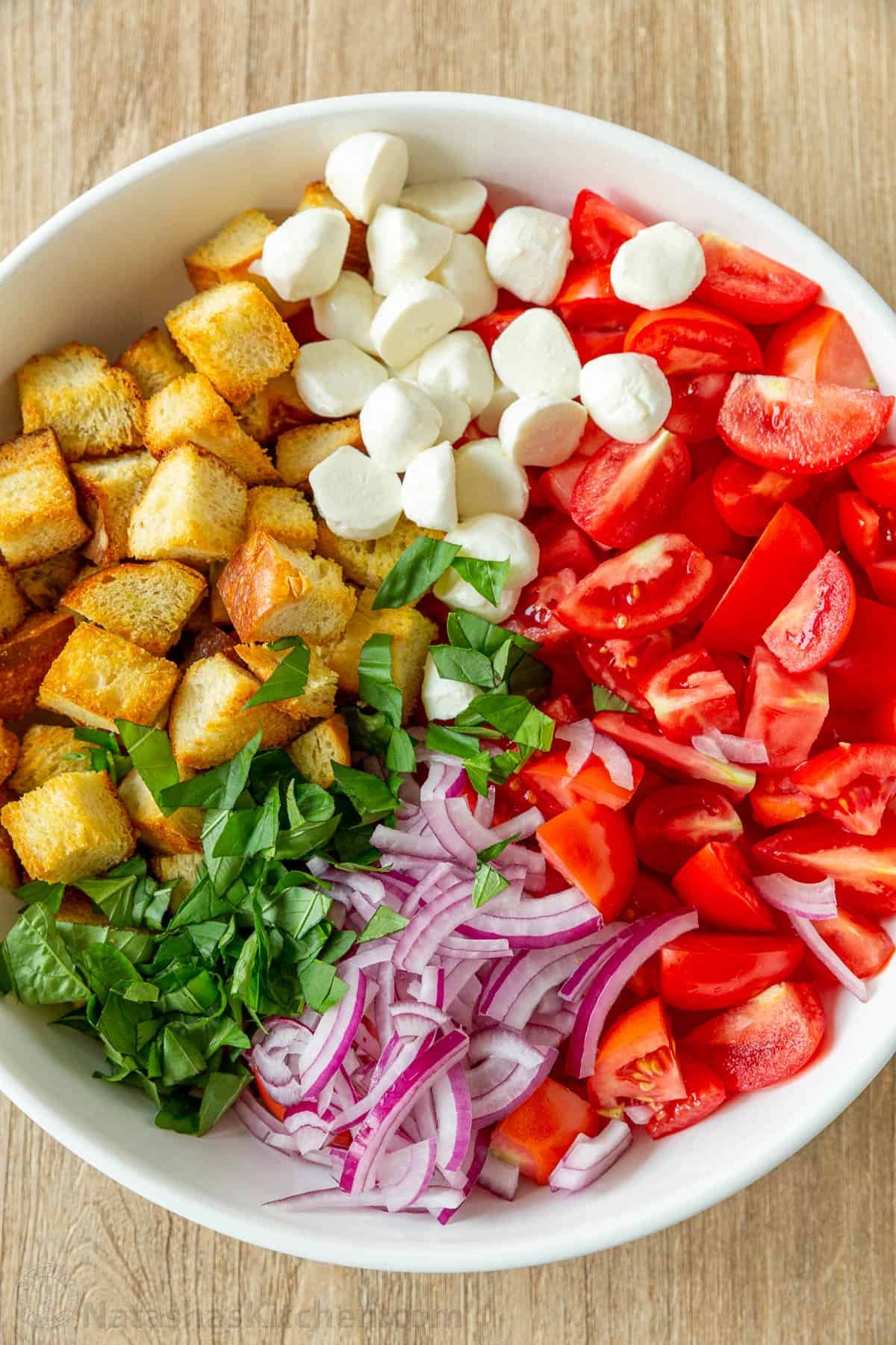 Panzanella Salad ingredients arranged in bowl with toasted bread, tomatoes, basil, onion and cheese