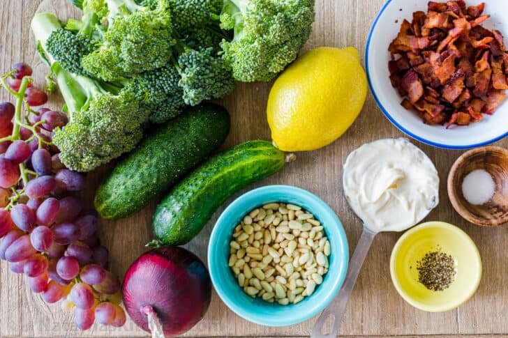 Ingredients for broccoli grape salad with broccoli, cucumber, grapes, bacon, red onion and dressing