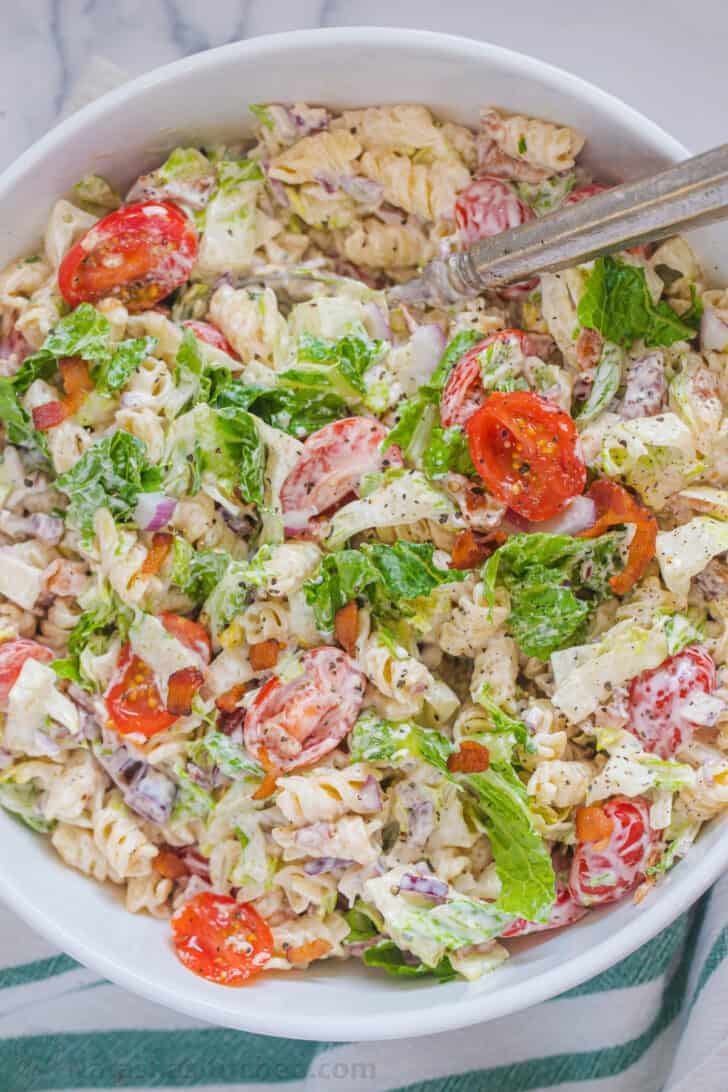 A white bowl with blt pasta salad topped with ground black pepper.