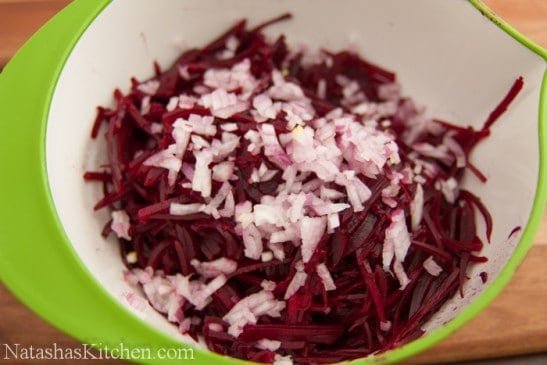 Diced red onions added to a bowl with julienned beets 