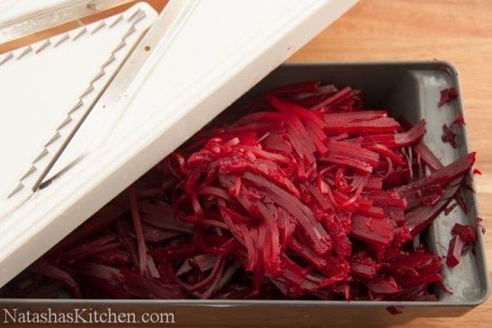 A mandolin being used to julienne beets
