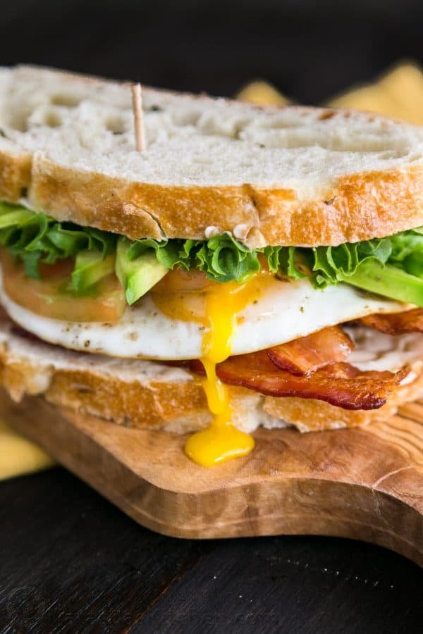 A close up of a breakfast BLT sandwich on a cutting board 
