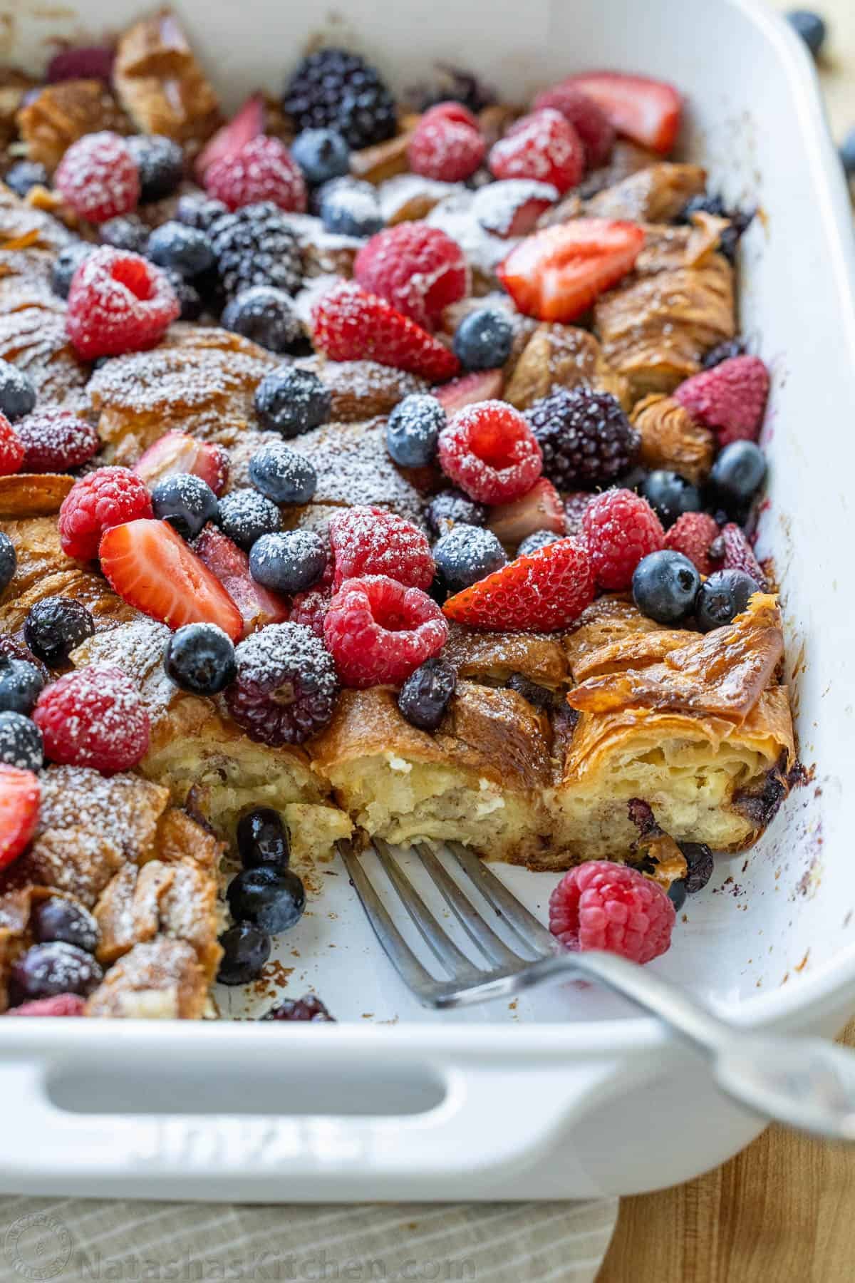 slice out of a berry-topped breakfast casserole with strawberries, blueberries, and blackberries