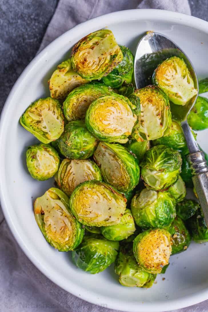 The easiest recipe for Air Fryer Brussels Sprouts, ready in less than 30 minutes. Crispy on the outside, soft and flavorful on the inside. Air Fryer Brussels sprouts on serving plate