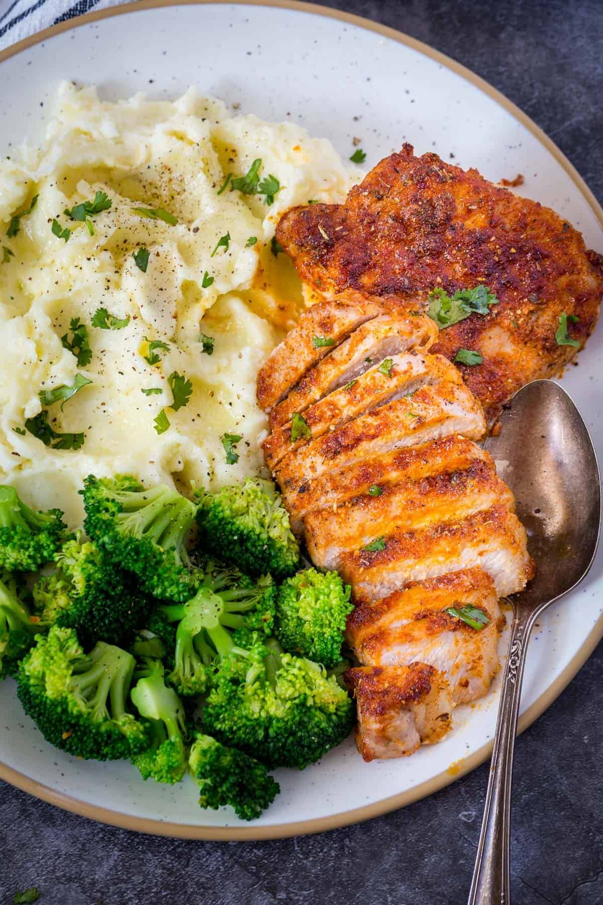 Air fryer pork chops recipe on a plat with Mashed potatoes and broccoli