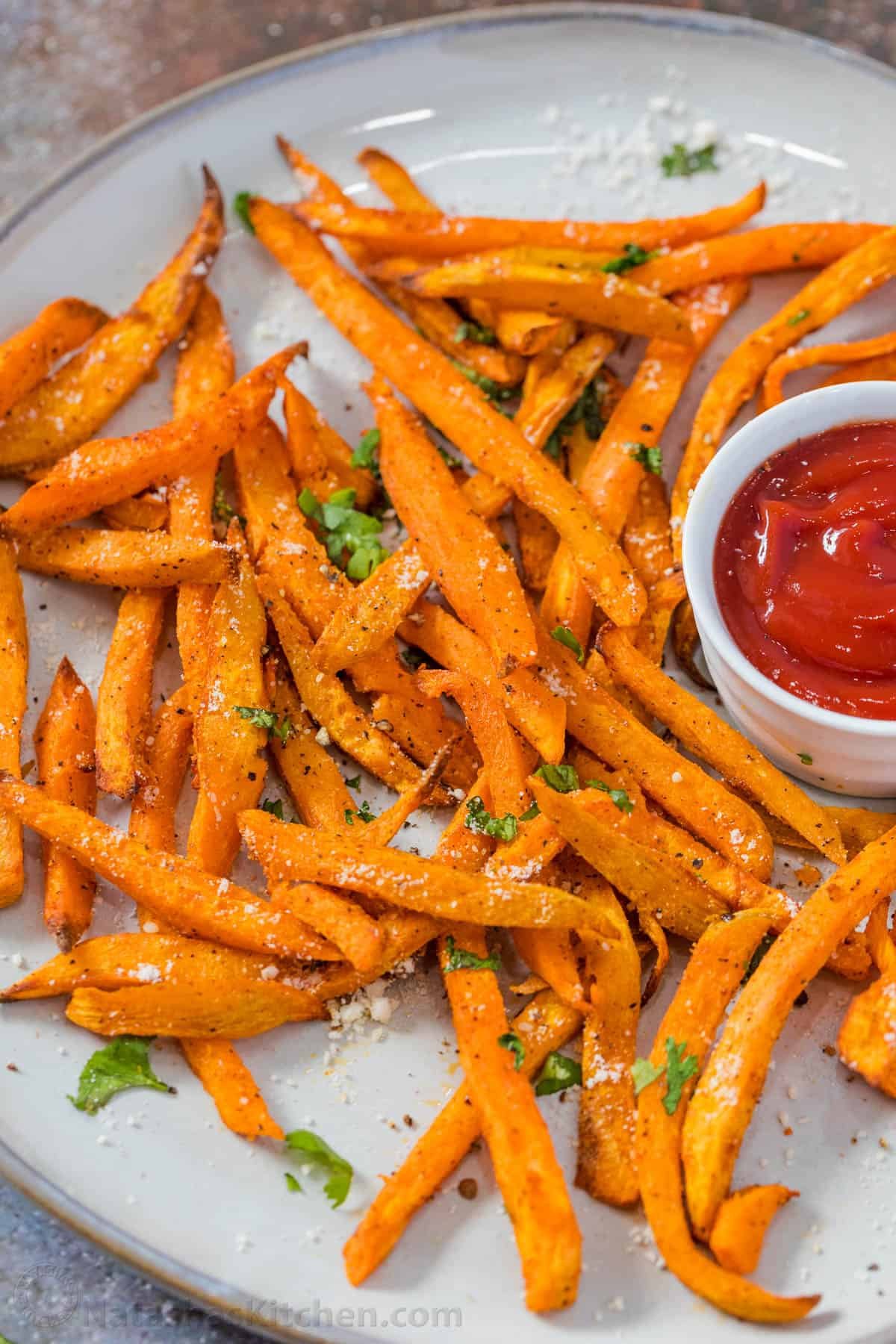 Air fryer Sweet potato fries on a white plate with a side of ketchup. 