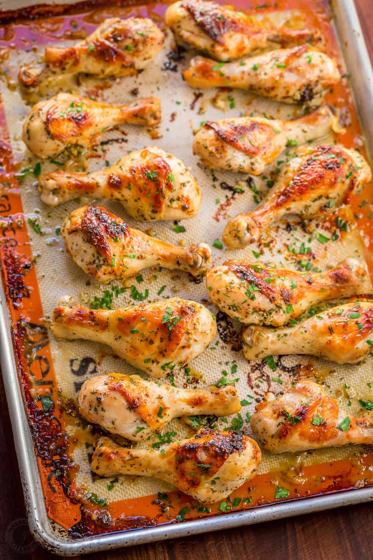 Baked Chicken Legs recipe with garlic, lemon and dijon. An easy and excellent chicken marinade with so much flavor. Learn the secret to great chicken legs! #bakedchicken #bakedchickenlegs #chickendrumsticks #ovenbakedchicken #bakedchickenrecipes #chickenrecipes #chicken Baked Chicken Legs on Baking Sheet garnished with parsley