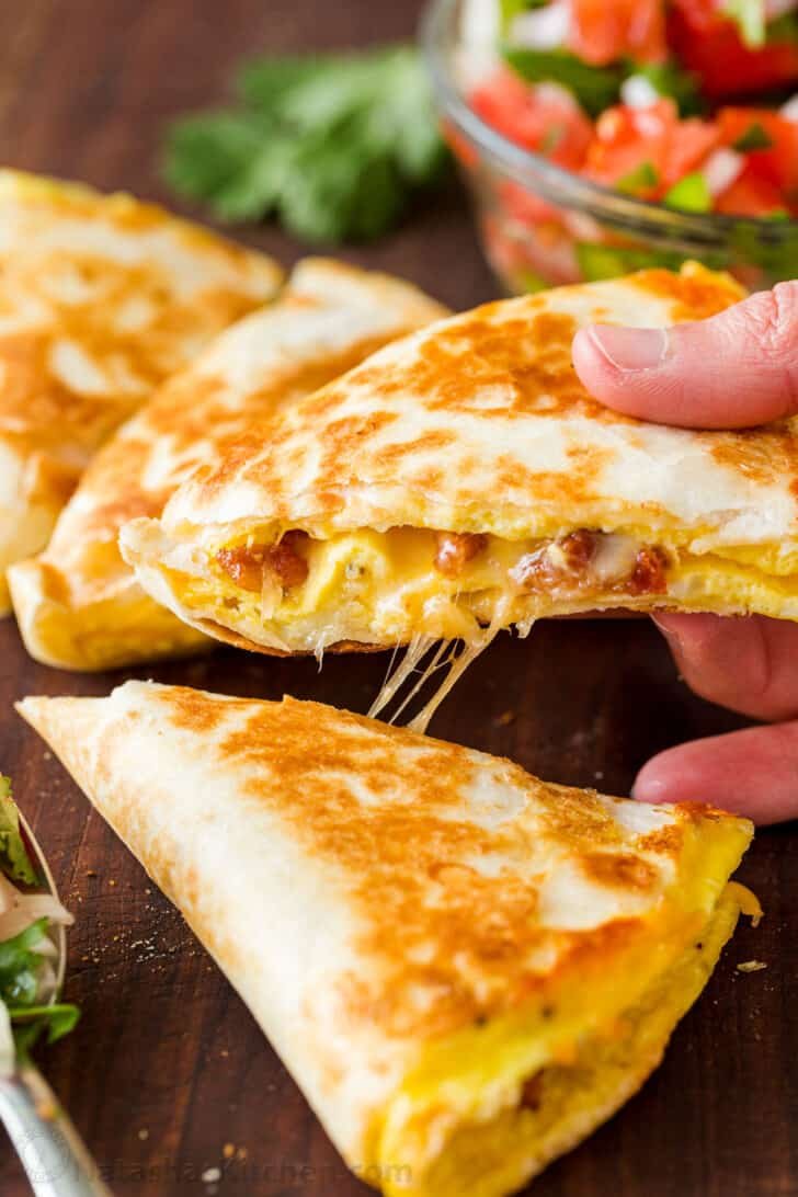 Breakfast quesadilla cut into wedges and lifted with cheese pull