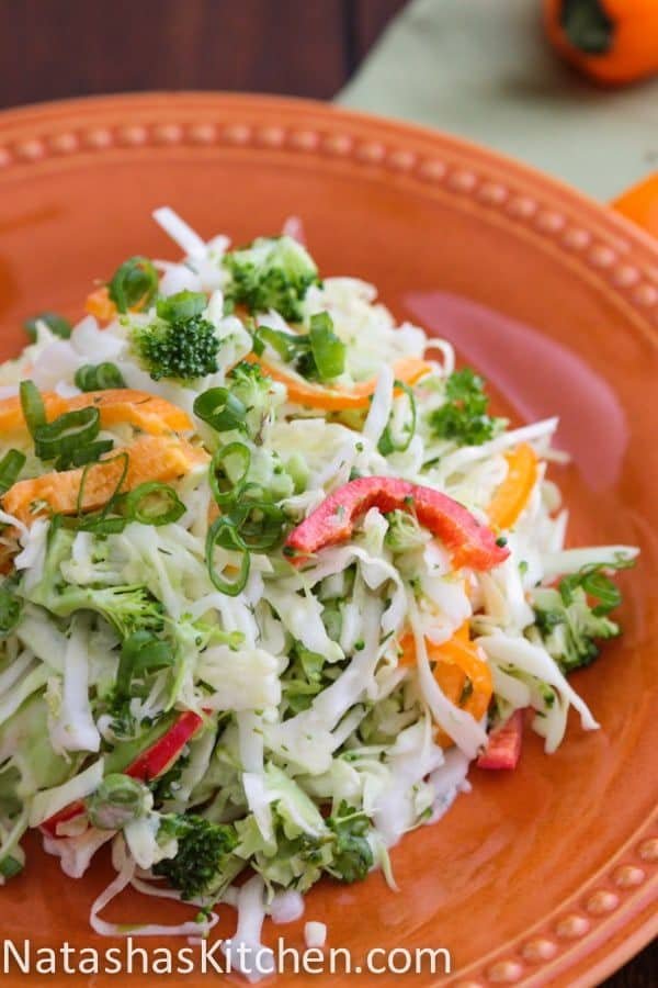 An orange plate with cabbage and bell pepper salad 