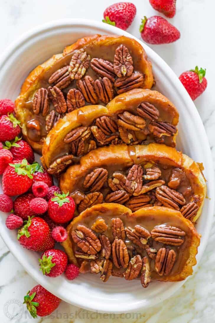 Slices of Caramel French Toast arranged on a platter and served with berries
