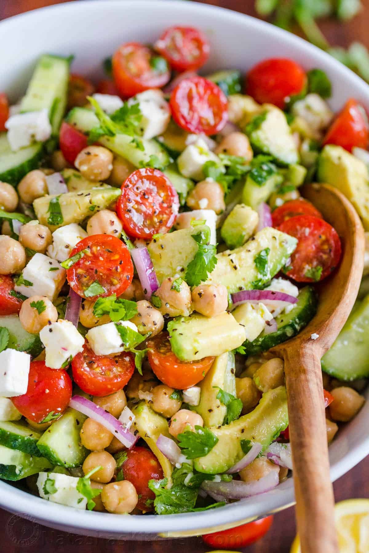 Chickpea Salad loaded with crisp cucumbers, juicy tomatoes, creamy avocado, feta cheese and chickpeas or garbanzo beans. Fresh, healthy and protein packed! #chickpeasalad #garbanzobeansalad #chickpeas #chickpeasaladrecipe #salad #saladrecipe #fetacheese #tomatosalad #avocadosalad #greeksalad #mediterraneansalad #natashaskitchen Chickpea Salad Recipe in a bowl with avocados, tomatoes, chickpeas and feta cheese